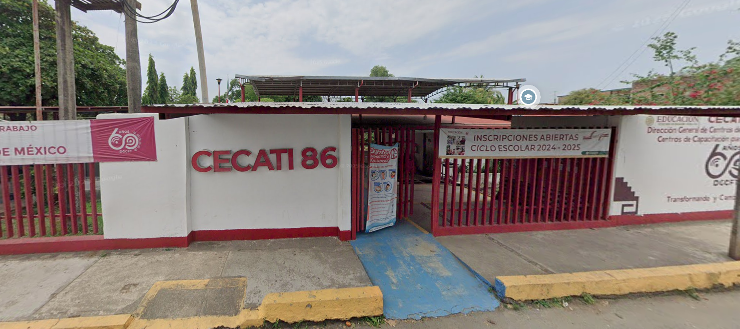 Fotografía en la que se muestra la entrada del plantel, conformada por una reja de color rojo y muros blancos. Del lado izquierdo de la reja, en un muro hay unas letras rojas grandes que dicen CECATI 86. Frente a la reja hay una rampa de acceso al plantel. 